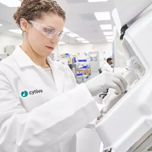 Scientist outfitted in PPE places a cell bag into the Xuri cell expansion system