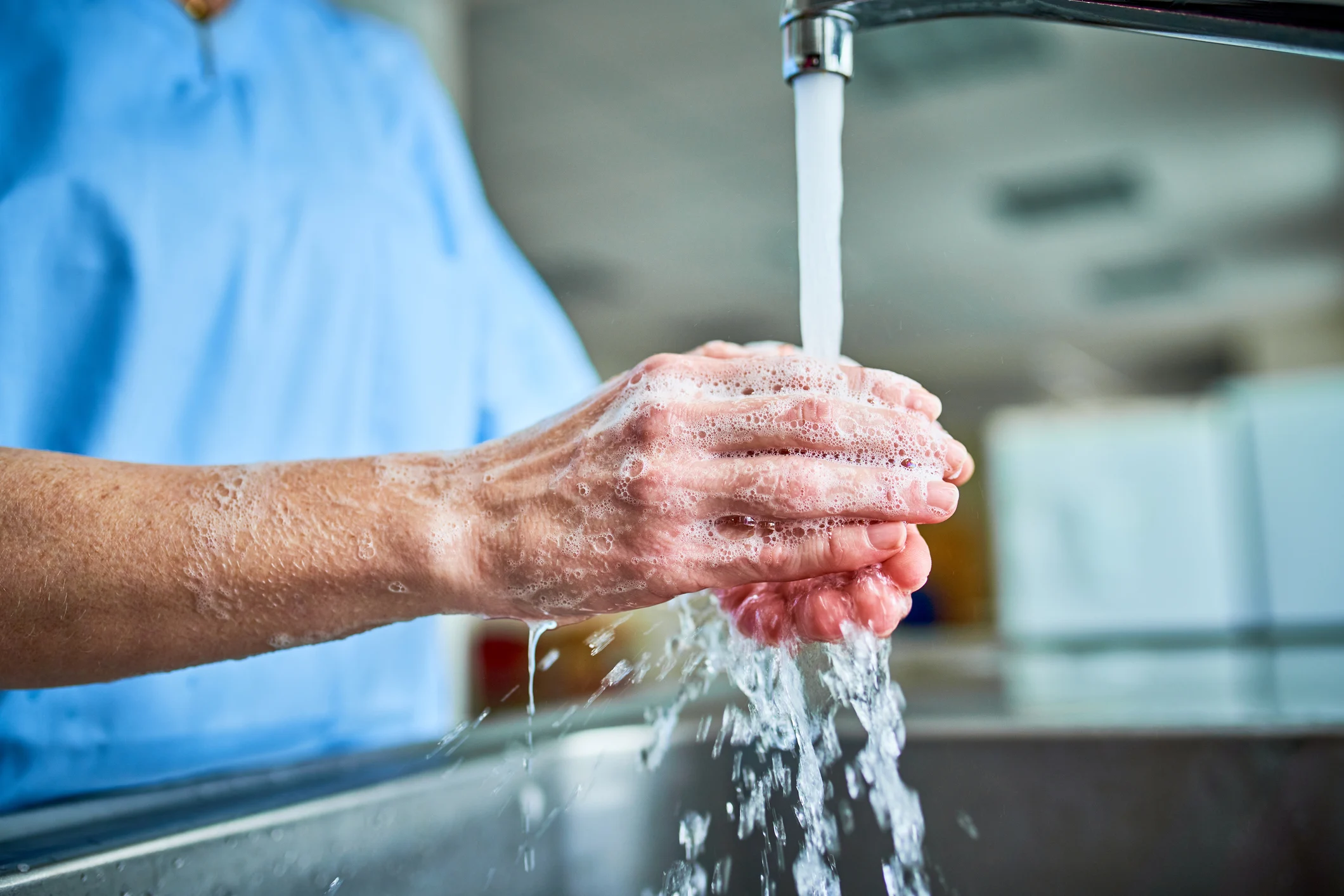Person washing hands under clean, filtered water from a Pall Medical faucet filter