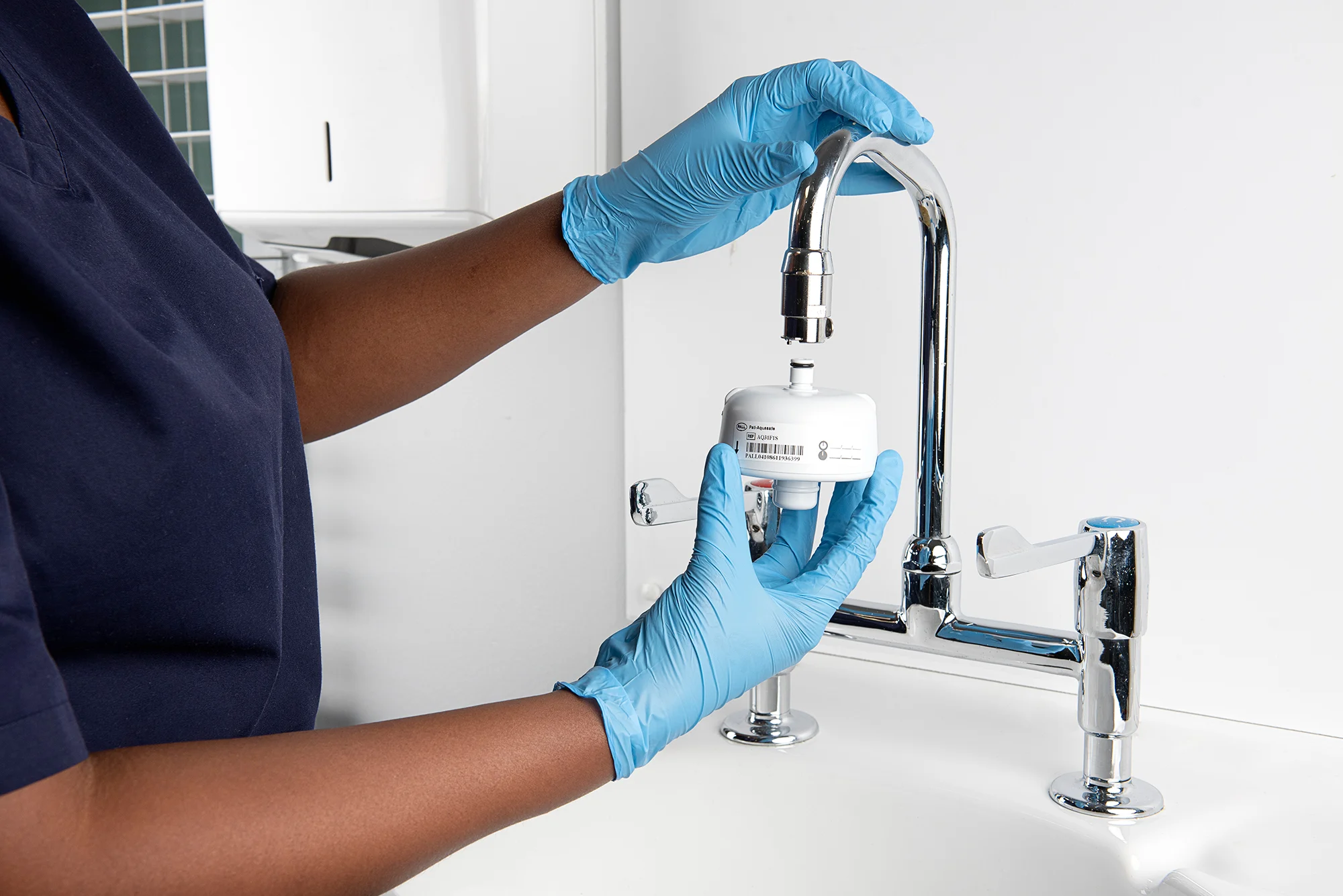 Healthcare staff member using a faucet with an installed Pall Aquasafe filter.