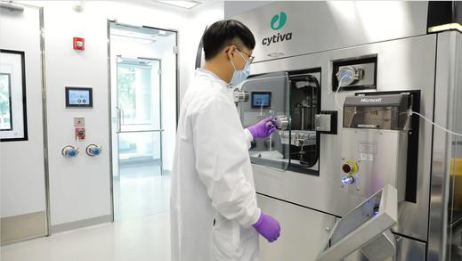 An operator prepares to take a finished nest of containers out of the Microcell Vial Filler installed in a pharmaceutical cleanroom