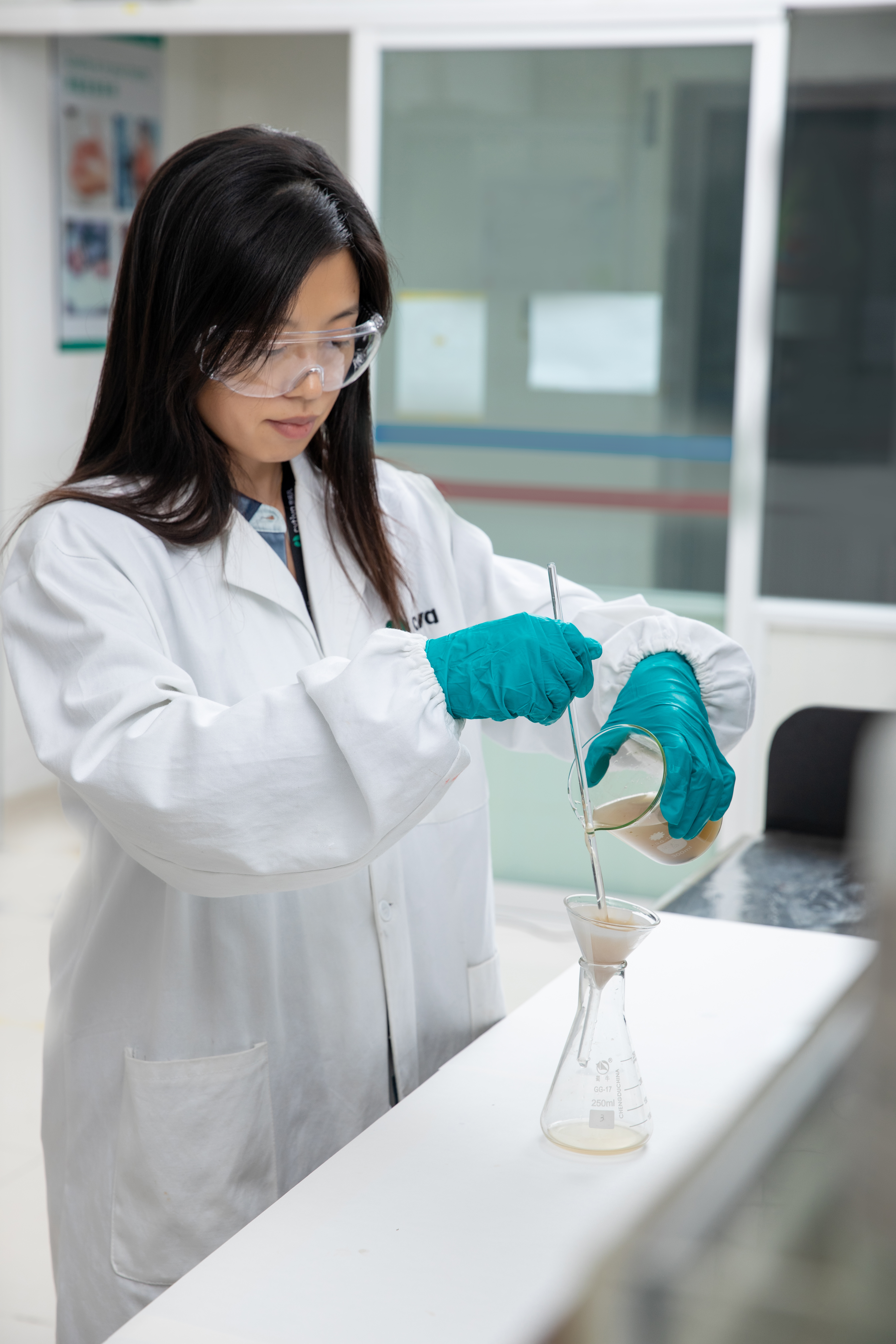 Scientist pouring liquid through filter paper into flask with filtration shown